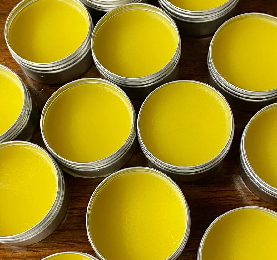 round open tins of yellow dandelion salve