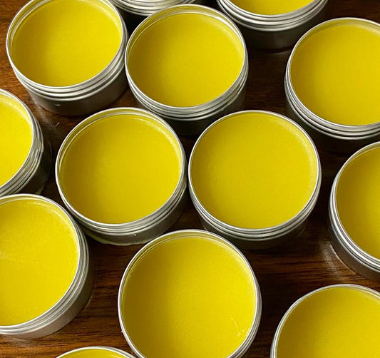 round open tins of yellow dandelion salve