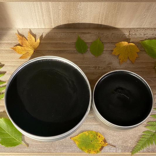 Two metal containers with black contents on a wooden surface