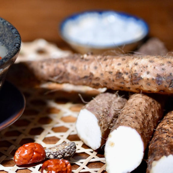 Bowl of Chinese yam soup with ingredients on a wooden table