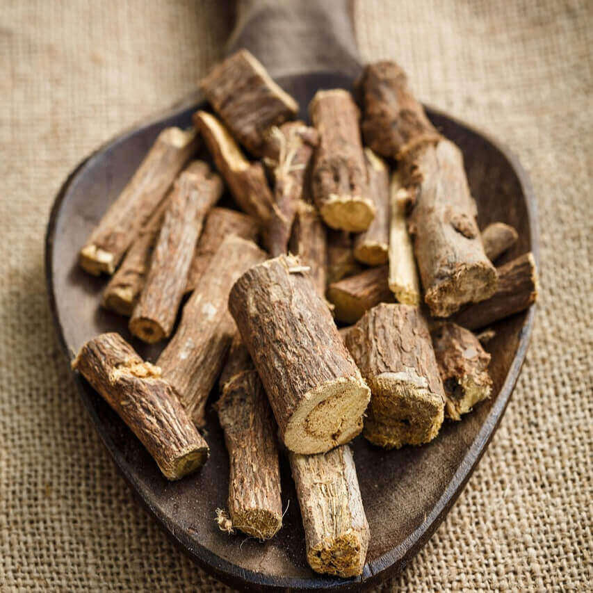 Wooden scoop filled with dried root pieces on a textured fabric background