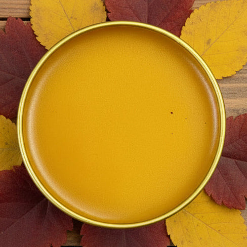 Pepperpot Pain Salve. Round mustard-colored ceramic plate on a textured brown surface