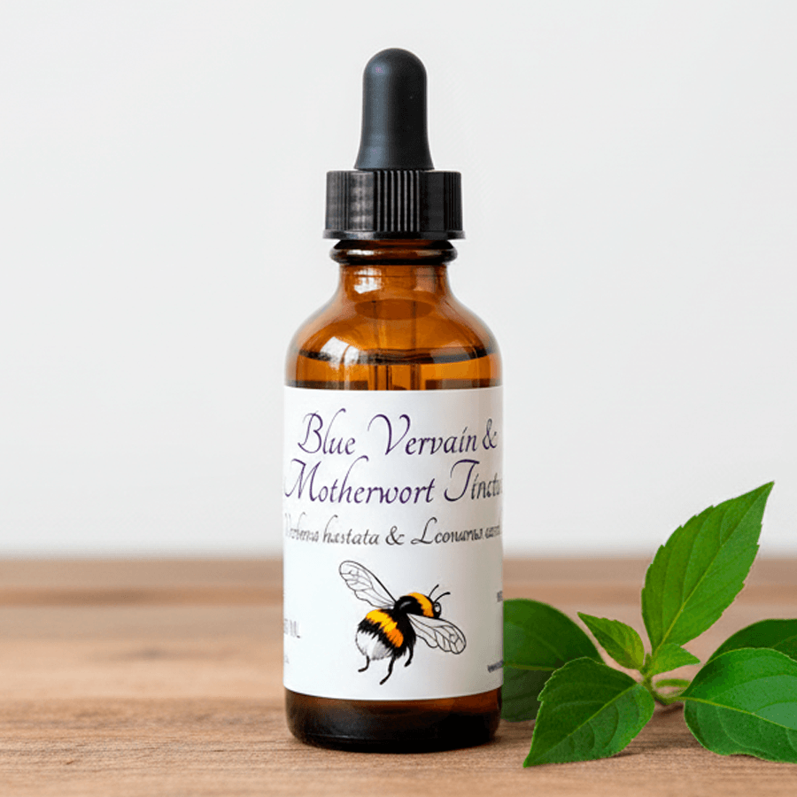 An amber glass dropper bottle with a black cap and a white label reading 'Blue Vervain & Motherwort Tincture,' shown on a wooden surface with green leaves beside it.