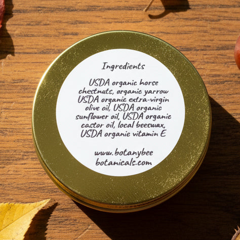 Gold lid of a cosmetic product with a white label listing ingredients on a textured surface.