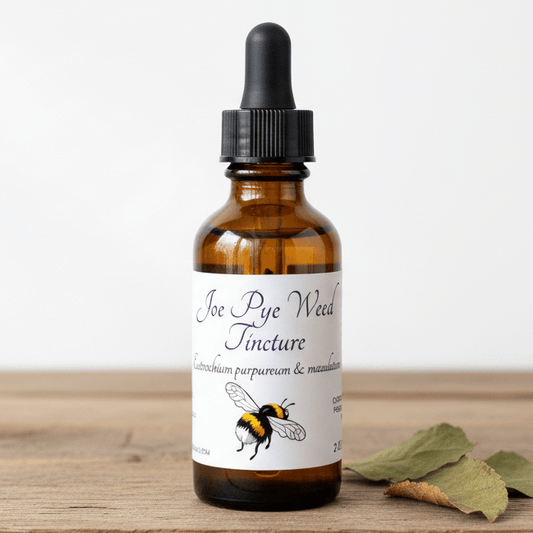 An amber glass dropper bottle labeled 'Joe Rye Weed Tincture' with a black dropper cap, standing on a wooden surface with dried green leaves beside it against a plain light background.
