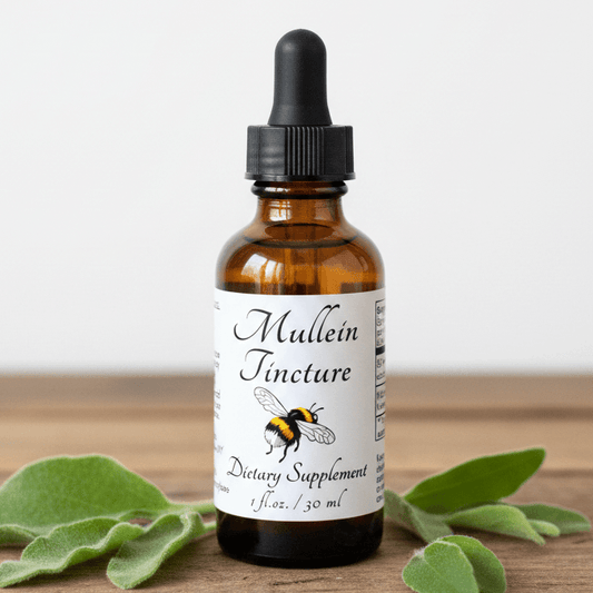 An amber glass dropper bottle labeled 'Mullein Tincture' with a black cap, standing on a wooden surface with green leaves around it against a light background.