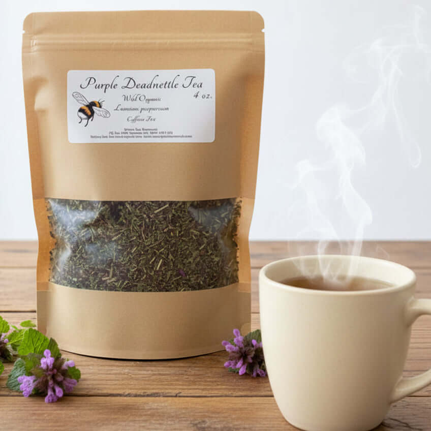 Brown paper tea bag with 'Purple Deadnettle Tea' label on a wooden surface with purple flowers.