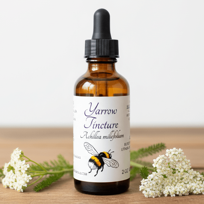An amber glass dropper bottle labeled 'Yarrow Tincture' with a black cap, set on a wooden surface with white yarrow flowers on both sides.